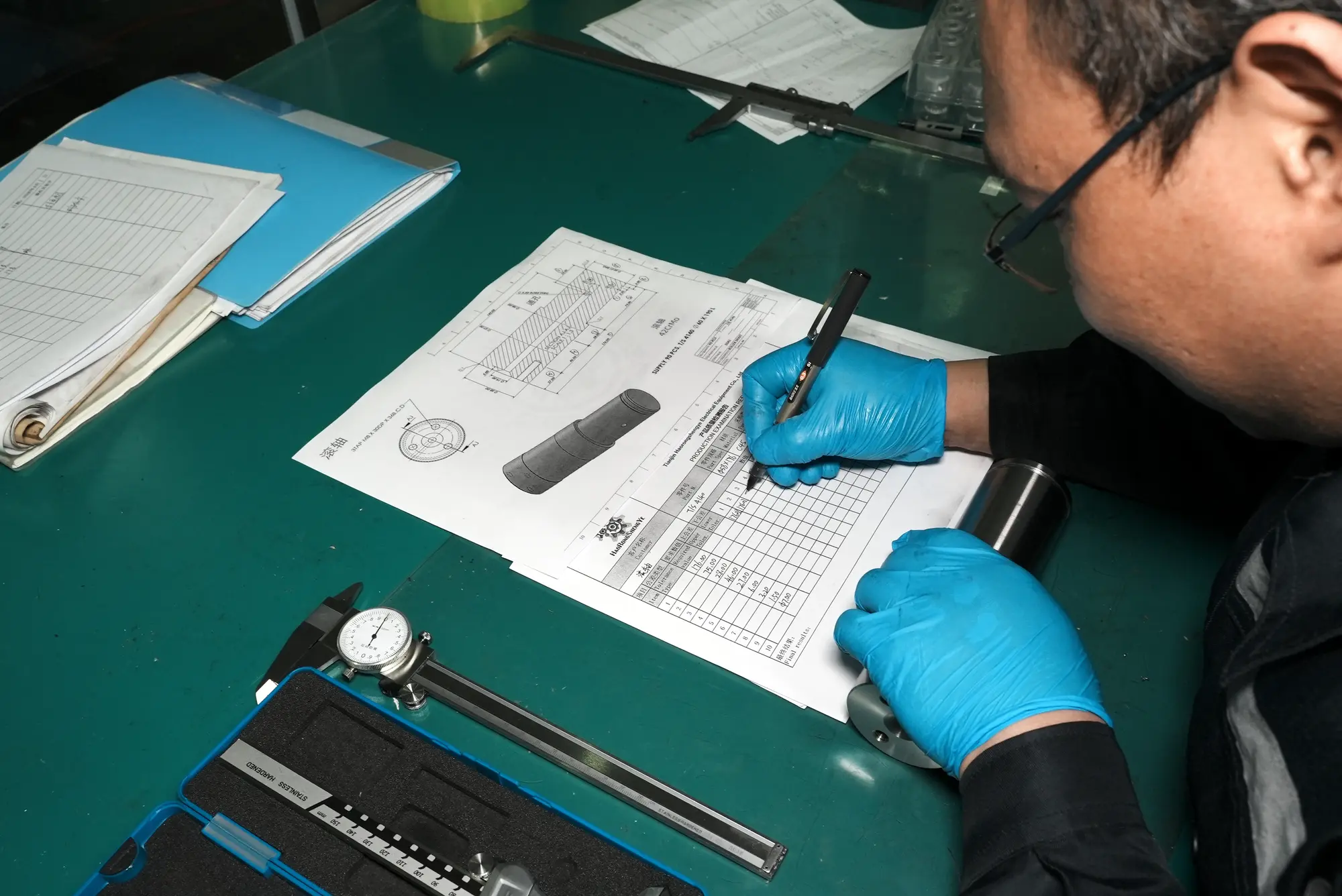 Inspector completing a dimensional record beside a part drawing